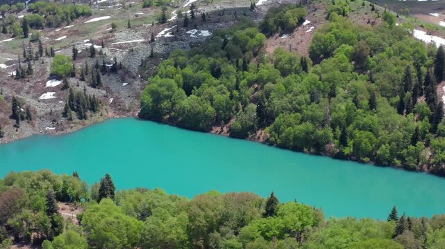 Aerial drone moves sideways around Green Lake near Goderdzi in Georgia, revealing turquoise water, wooded banks and alpine slopes for ecotourism, destination media and outdoor recreation campaigns.