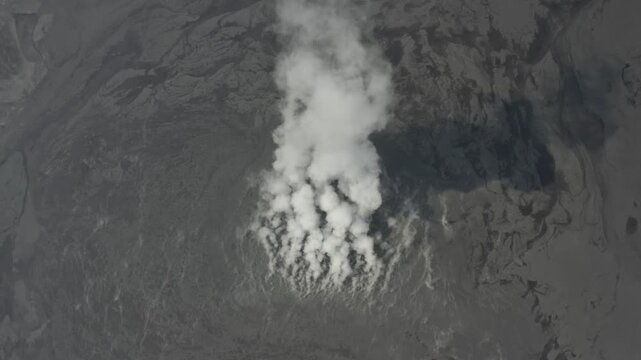 Kecamatan Porong, Indonesia - 22 July 2026: Aerial view of the Lumpur Lapindo mud volcano emitting thick white steam over the dark, textured landscape of the disaster site.