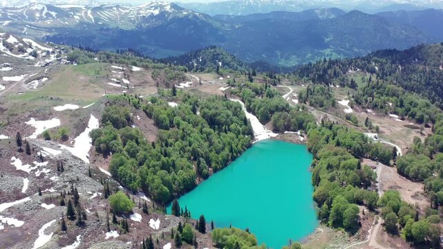 Green Lake appears in broad aerial view beneath Caucasus ridges, forest and seasonal snow in Upper Adjara, supporting regional tourism, mountain geography, travel campaigns and destination discovery.