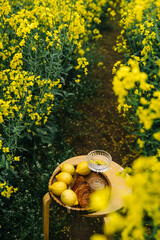 Lemons and croissants set on a small table among vibrant yellow flowers in the countryside