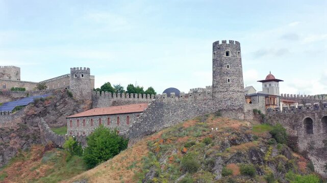 Akhaltsikhe Castle circles through elevated aerial view across fortified walls, towers, mosque dome and hillside grounds, supporting Georgian heritage travel, architecture media and cultural tourism.