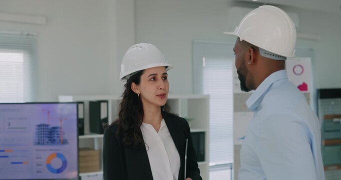 Portrait of multiracial construction engineers discuss project in building company office. Hispanic woman and African American man contractors talk at meeting