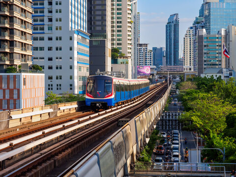 Bangkok, Thailand - July 8, 2026 : The BTS Skytrain runs in and out of Victory Monument Station in the afternoon, showing the other side of the station with stunning views of Bangkok office buildings.