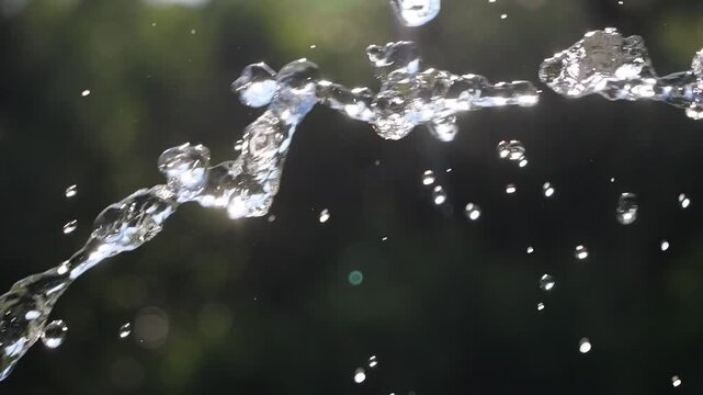 A jet of water flies in the air with splashes. Water drops in the summer.