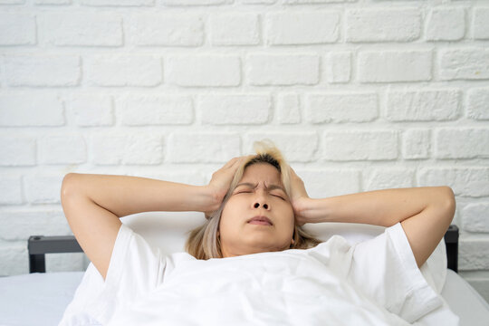Asian woman experiences stress while lying in her bedroom. Concepts related to negative emotions and mental health.