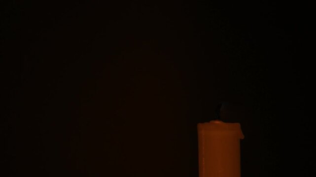 small dying candle flame in right corner on black background