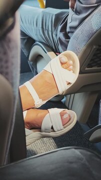Disrespectful traveler placing their bare feet in sandals on the seat in front of them while riding public transportation