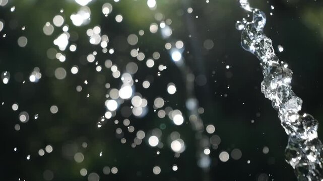 A jet of water flies in the air with splashes. Water drops in the summer.