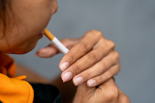 The concept of smoking. A woman lights a cigarette with a lighter. Smoking. Close proximity.
