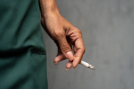 Asian woman's hand holding a cigarette outdoors. Women's health concept.