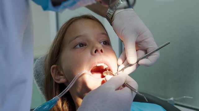 Pediatric dentist examining teeth with mirror and probe for young girl