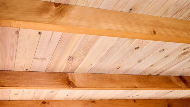Interior view showcases rustic wooden ceiling crafted from natural Douglas fir timber planks with parallel exposed beams creating warm geometric architectural pattern inside cottage log home.