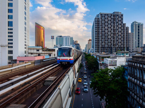 Bangkok, Thailand - July 8, 2026 : The BTS Skytrain runs in and out of Saphan Kwai Station in the afternoon, also offering views of Bangkok's beautiful office buildings.