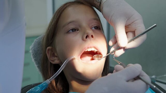Pediatric dentist examining teeth with mirror and probe for young girl