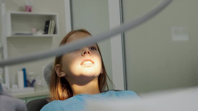 Pediatric dentist polishing tooth filling with handpiece for young girl close up