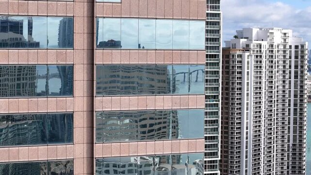 Miami, Florida, United States - 18 July 2026: Aerial view of the glass facade of a skyscraper in Downtown Miami reflecting the surrounding urban skyline and bay.