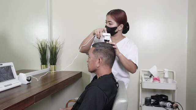 Digital scalp analyzer scanning a healthy middle aged man&rsquo;s scalp with live follicle imaging display for scalp diagnosis and hair care assessment.