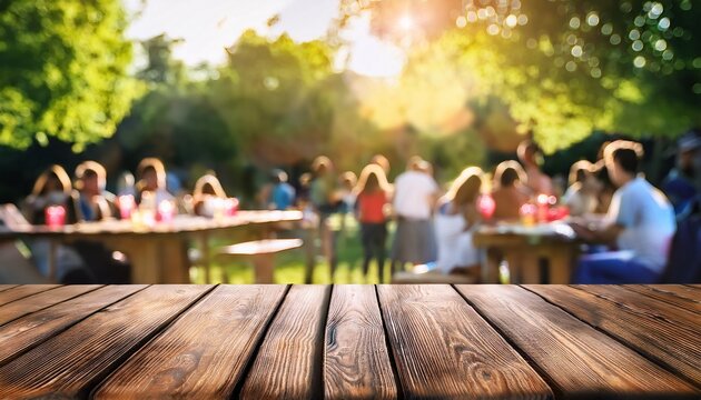 empty wooden table in summer background with the blurred green garden and party in the background
