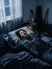 Fototapeta premium Caucasian man musician sleeping restlessly with open mouth on bed in dark bedroom. Sleep apnea and chronic fatigue awareness vertical banner