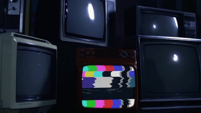 Stacked Vintage CRT Televisions Turning On with Glitching Color Bars in Dark Room - 4K
