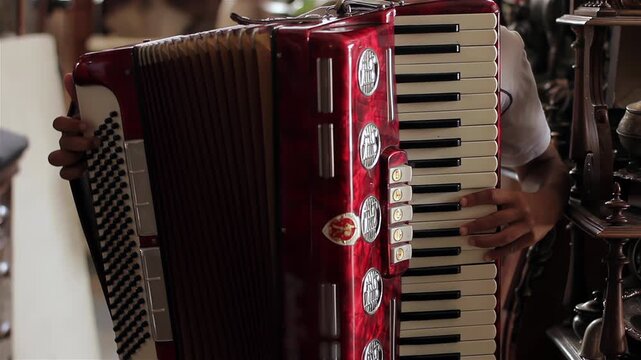 Close Up of Teenage Boy Hands Playing Red Accordion Keyboard - 4K
