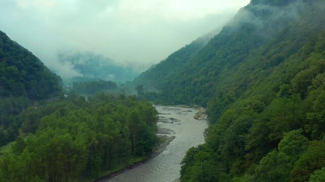 Drone flies forward along the Aragvi River in Georgia, tracing braided water channels between forested mountains for nature tourism, watershed research and environmental documentary projects.