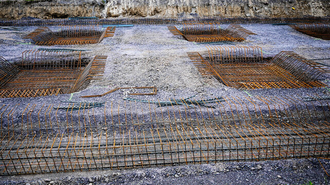Rebar cages sitting in gravel base, preparing for concrete pouring on an industrial building foundation