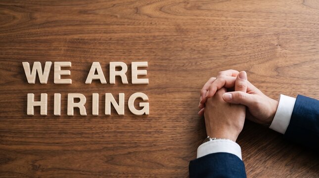We Are Hiring message in wooden letters on office desk, recruitment and job vacancy concept, businessman hands waiting for interview
