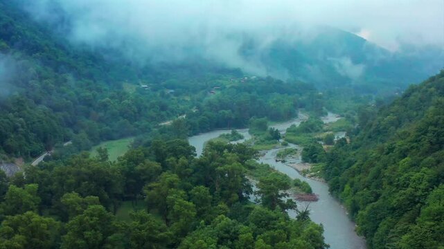 Aragvi River branches through aerial view across wooded islands and misty mountain slopes in Georgia, supporting floodplain research, river ecology, tourism campaigns and landscape mapping media.