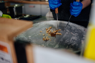 Fototapeta premium Dessert vendor arranging freshly made rolled ice cream curls on a freezing metal plate