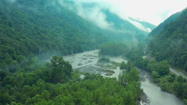 Aragvi River spreads through aerial view across gravel bars, wooded islands and a foggy Caucasus valley, supporting flood risk studies, hydrology research, ecotourism and Georgian geography media.
