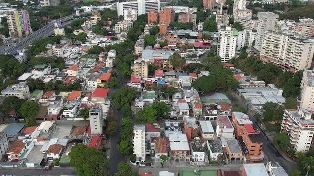 Caracas, Venezuela - 29 January 2025: Aerial view of the dense urban landscape of Petare with residential buildings, lush trees, and winding streets.