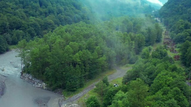 Aragvi River bends through aerial view beside a wooded riverside clearing and access track in Georgia, supporting camping tourism, recreation planning, riparian research and regional travel media.