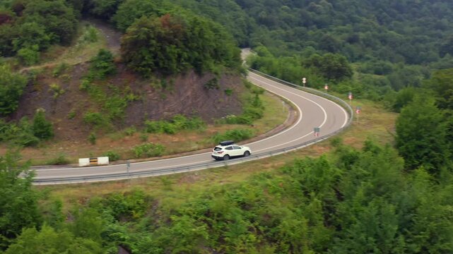 Car travels through aerial view along a winding forest road near Zhinvali Reservoir in Georgia, supporting road trip advertising, route planning, mountain tourism and regional transport geography.
