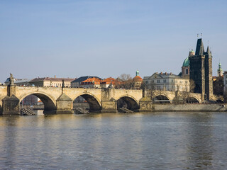 Obraz premium View of an old stone arch bridge over a river in Prague Praha European city seen from the below on the water with architectural beauty