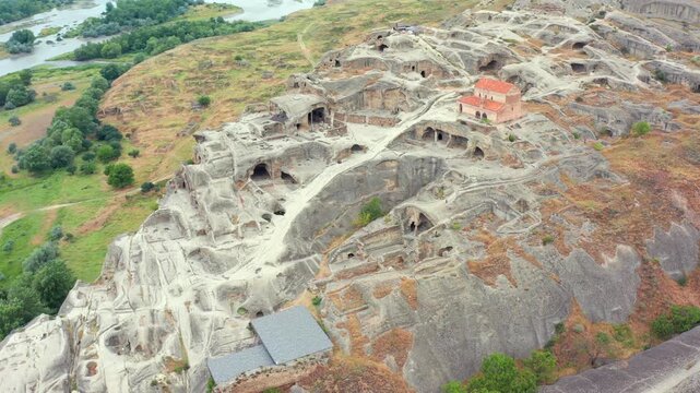 Ancient Uplistsikhe unfolds in overhead aerial view across excavated caves, pathways and a hilltop church, supporting site mapping, heritage conservation, archaeology and cultural tourism promotion.