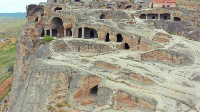 Uplistsikhe cave chambers fill aerial view across weathered rock facades and ancient entrances near Gori, supporting archaeology tourism, heritage education and Georgian history documentary media.