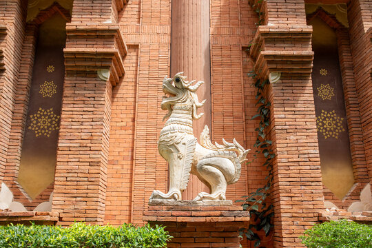 White guardian lion statue standing at ancient Cham brick tower with carved patterns in Vietnam