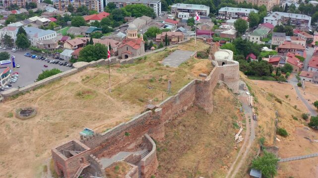 Aerial drone moves sideways around Gori Fortress in Georgia, presenting the fortified hill, city center and residential districts for cultural tourism, urban history and landmark promotion media.