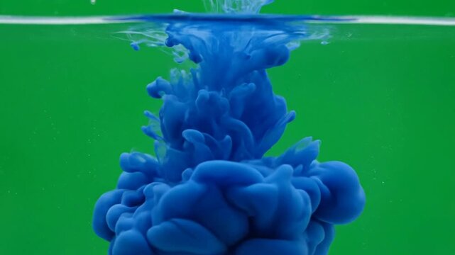 Blue ink drop dissolving in water on green background, abstract liquid motion for creative projects and visual effects