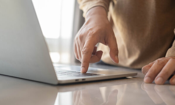 Close up of hand using laptop touchpad in modern workspace with soft natural light. Digital technology, online business, remote work and professional productivity concept for contemporary lifestyle.