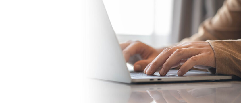 Close up of hands typing on laptop keyboard at modern workspace with copy space. Remote work, online communication, business technology and digital productivity concept for professional lifestyle.