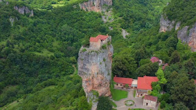 Katskhi Pillar centers overhead aerial view above monastery courtyards and forested terrain, supporting site mapping, sacred architecture, cultural conservation and Georgian tourism campaigns.