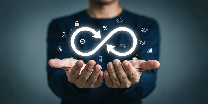 Business professional hands displaying infinite loop workflow icon with various technology symbols.