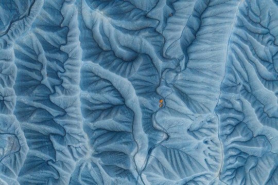 Aerial view of the intricate, eroded blue-grey clay formations of the badlands, featuring deep ridges and gullies with small patches of orange sediment in Hanksville, Utah, United States.