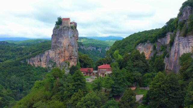 Katskhi Pillar rises in broad aerial view above forested cliffs and monastery grounds near Chiatura, supporting religious travel, regional tourism, cultural history and destination campaigns.
