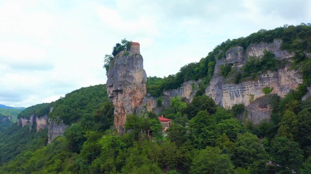 Katskhi Pillar anchors sweeping aerial view beside limestone walls and dense woodland in Imereti, supporting geotourism, Orthodox heritage, conservation studies and Georgian travel promotion.
