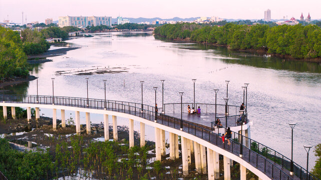Iloilo City, Western Visayas, Philippines - 18 July 2026: Aerial view of Iloilo Sunset Boulevard with people on the boardwalk, surrounded by mangroves and the river under a soft evening sky.