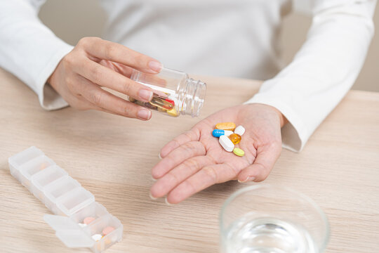Sick asian young woman, girl holding tablet pill on hand pour capsule from medication bottle, painkiller medicine from stomach pain, headache, pain for treatment, take drug or vitamin, health care.