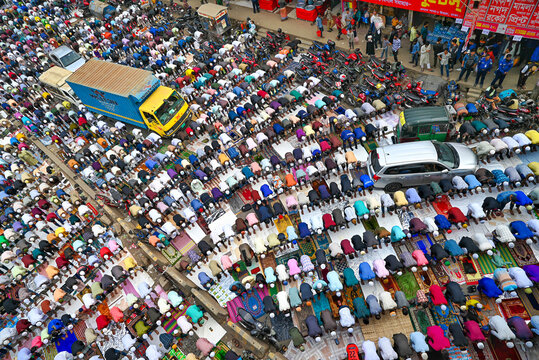 Tongi, Dhaka Division, Bangladesh - 31 January 2025: Aerial view of Tongi Ijtema Maidan with a large crowd of worshippers praying on mats amidst parked vehicles and urban surroundings.
